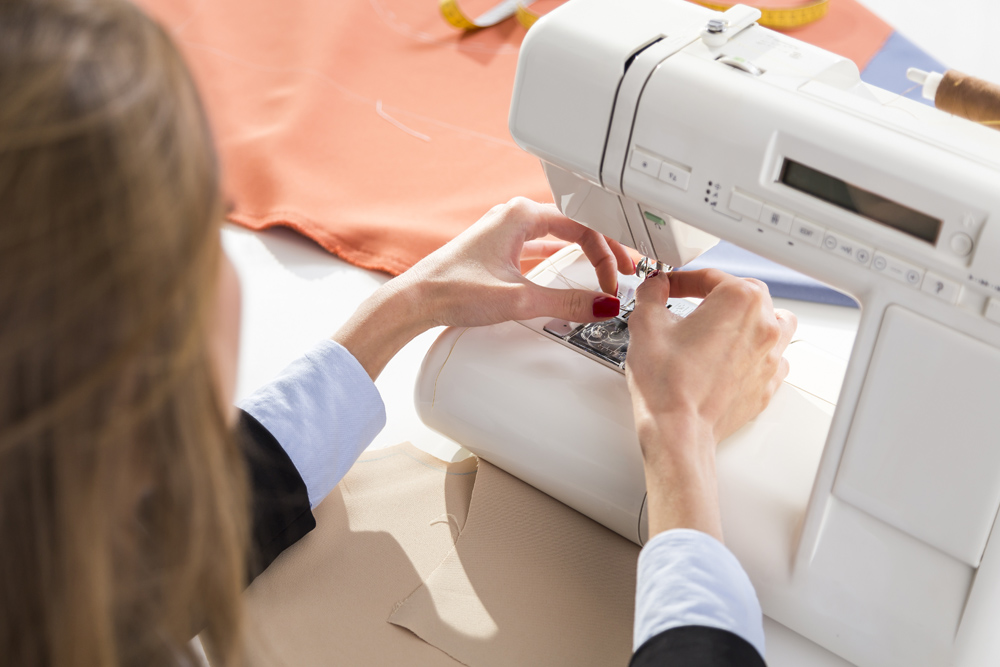 Hands at sewing machine holding some fabric
